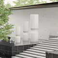 White Cylindrical Textured Sculptures Against Gray Wall With Green Trees Black Platform And Steps
