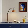 Adjustable Desk Lamp with Orange Shade on Blue Cabinet Open Book Yellow Vase Wall Painting