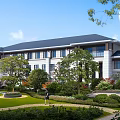 Modern Office Building Exterior with Gray Roof White Facade Large Windows Portico and Landscaped Lawn