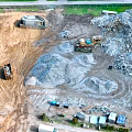 Aerial Planning View Of Construction Site With Sand Piles Trucks And Materials