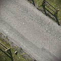 Road Infrastructure Cracked Asphalt Pavement With Grass Verge And Wooden Fence