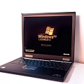 Classic Black Laptop Displaying Windows XP Login Screen on White Background