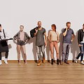 Six People Standing in a Line Against White Wall and Wooden Floor With Diverse Outfits