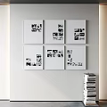 White Framed Black And White Photos Arranged On White Wall With Stacked Books