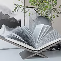 Decorative Ornament Set With Open Book Stacked Books Gray Vase Green Foliage And Framed Artwork
