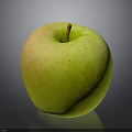 Fresh Yellow Green Apple With Speckled Surface Brown Stem On Shiny Surface With Gray Background