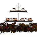 Three Tiered Cupcake Stand With Assorted Cupcakes And Red Green Leaf Decorations