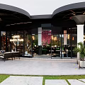 Modern Café With Curved Roof Glass Walls Outdoor Seating And Greenery Decor