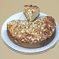 Freshly Baked Round Cake With Nut Toppings On White Plate And Sliced Piece