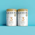 Blackmores Toddler Formula Stage 3 In White Cans With Gold Lids On Blue Background