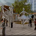Vibrant Urban Commercial Street with Ballerina Sculptures Pedestrians Modern Buildings and Green Plants
