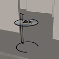 Modern Minimalist Side Table with Round Tempered Glass Top and Black Metal Frame Holding Magazine