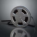 Vintage Style Metallic Film Reel With Black Film Strip On Smooth Reflective Surface