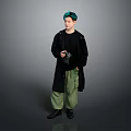 Man With Green Hair Wearing Black Coat And Green Pants Holding Camera Against Gray Background