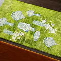 Green Square Rug With White Vase Plate And Flower Patterns On Dark Floor