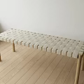 Light Colored Bench With Woven Surface And Wooden Legs On Wooden Floor Indoor