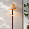 Red Pole Floor Lamp With Beige Lampshade Illuminating White Wall And Green Plant