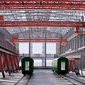 Industrial Factory Interior Featuring Red Cranes Green Train Carriages Metal Tracks And High Ceilings