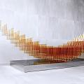 Wing Shaped Sculpture With Golden Orange Strips On Silver Base And Gray Wall