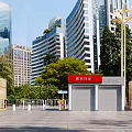 Entrance Gate Featuring Red Sign in Plaza with Modern High Rise Buildings and Green Trees