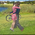 Couple Hugging Outdoors On Green Grassland With Lake And Bicycle
