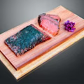 Two Green and Pink Meat Pieces with Purple Flower Garnish Served on Wooden Board
