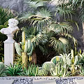 Tropical Garden With Lush Plants White Bust Statue Gray Wall Stone Path And Pebbles
