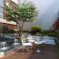 Serene Modern Garden Landscape Design With Fountains White Chairs Pink Flower Tree And Wooden Deck