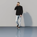 Man In Black Shirt And Light Blue Jeans Talking On Phone Against Gray Wall