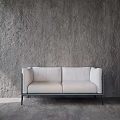 Modern White Two Seater Sofa With Metal Frame And Black Legs Against Grey Concrete Wall