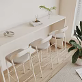 Minimalist Bar Counter With White Surface Three High Stools Light Gray Cushions And Green Plants