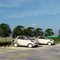 Electric Vehicle Parking Lot With Charging Stations And Green Trees Under Blue Sky