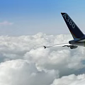Large Commercial A380 Airliner Flying Above White Puffy Clouds in Blue Sky