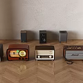 Multiple Vintage Headphones and Speakers Arranged on Wooden Floor with Gray Wall and Lighting