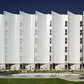 Modern White Building With Wavy Facade Windows Front Grass Swimming Pool And Lounge Chairs