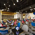 Modern Bar Interior Design With Open Layout Colorful Chairs Art Mural Chandeliers And Marble Tabletops