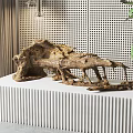 Natural Wooden Sculpture Displayed On White Striped Pedestal With Perforated Wall And Green Leaves