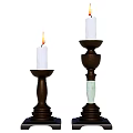 Lit White Candles On Two Dark Base Candle Holders With Green Columns And Different Heights