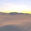 Desert Landscape with Rolling Sand Dunes Bathed in Sunset Light and Wispy Clouds