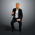Man Wearing Black Suit Holding White Cup Sitting Against Gray Background