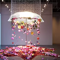 Floral Sculpture Installation with Hanging Colorful Flowers and Umbrella Like Structure and Scattered Petals on Floor