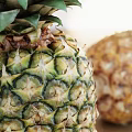 Two Pineapples One Standing and One Lying on Wooden Table with Marble Background and Sunlight