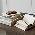 Stacked Books With Leather Pouch And Open Book On Wooden Table