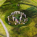 Ancient Stone Circle Structure with Wooden Elements in Lush Green Grassland Area