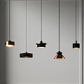 Five Black Pendant Lights with Various Shapes Hanging Some Illuminated Against White Wall