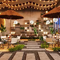 Outdoor Restaurant Design With Straw Umbrellas String Lights Stone Walls And Green Plants
