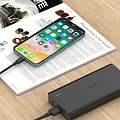 Smartphone Charging With Portable Power Bank On Magazine And Wooden Desk