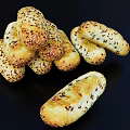 Golden Brown Bread Sticks Topped With Sesame Seeds Arranged In A Stack On Black Background