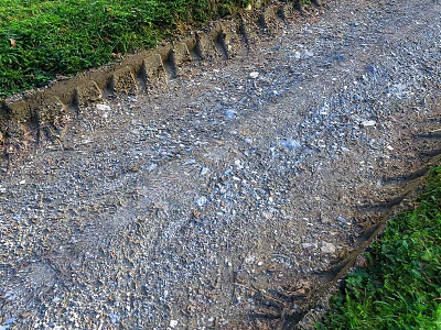 Rutted Gravel Ground With Grass Edges Visible Tire Tracks And Loose Stones 3d model