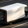 White Commercial Van With Black Trim Driving On Road With Open Rear Door